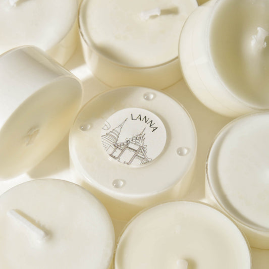 A collection of hand-poured tealights with a white wax layer, featuring a design on the top surface.